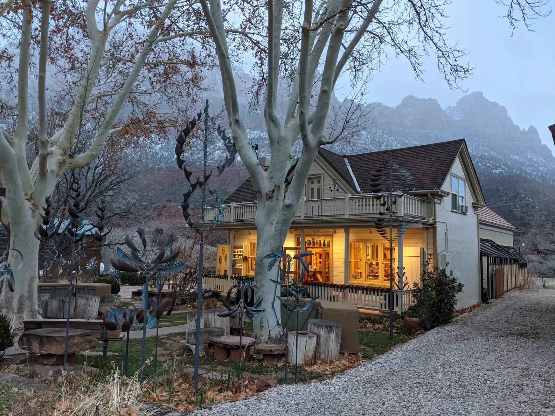 A lamplit cottage below misty red-rock peaks at dusk
