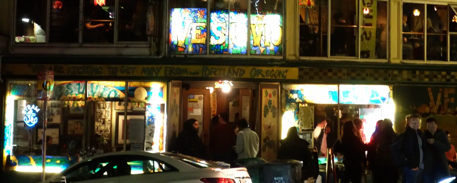 A lively corner storefront on a historic block at night