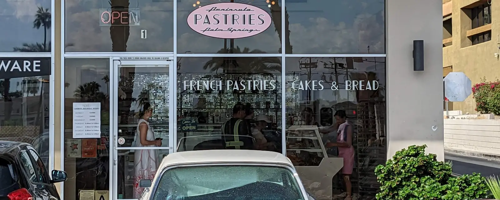 A vintage pastry shop with a classic car parked outside